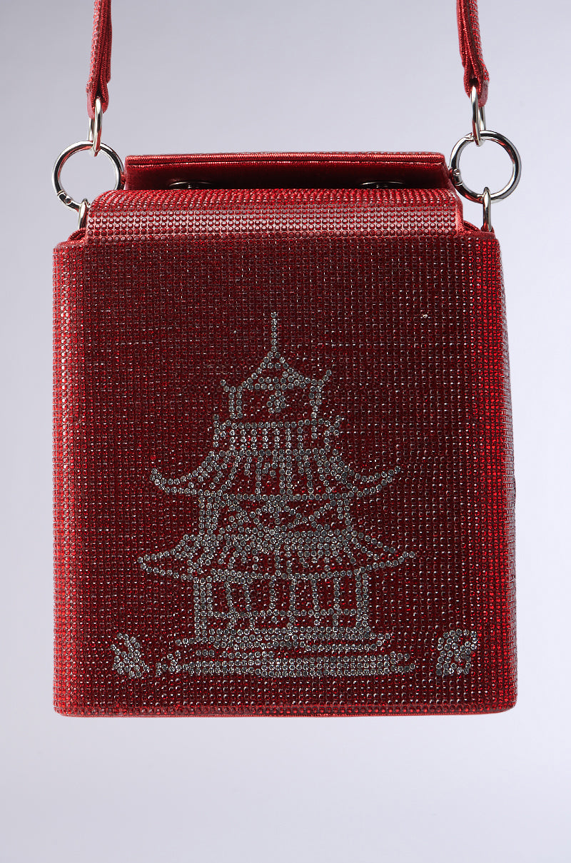 The TAKE ME AWAY BLING BAG is a small red bag with takeout box-inspired graphics, featuring shimmering rhinestone embellishments in a silver pagoda design, and includes a handle with silver rings on a plain white background. 3