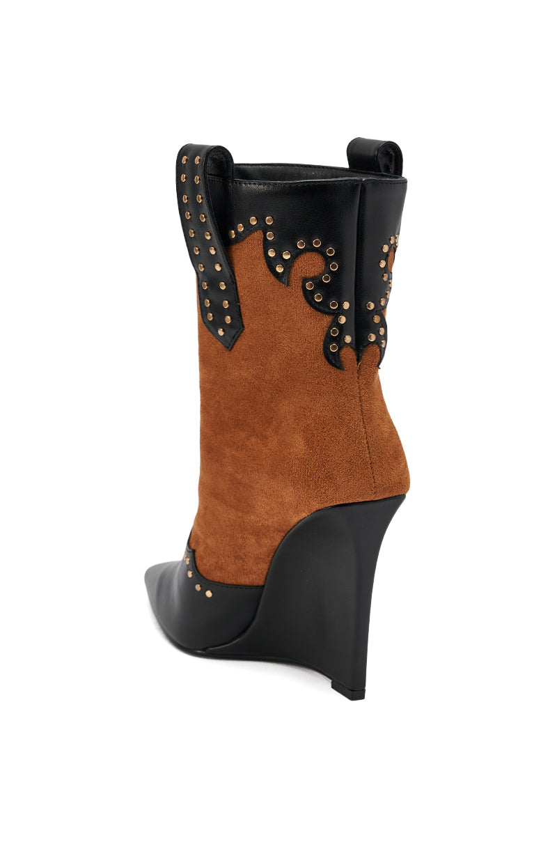The AZALEA WANG TALLULAH COGNAC WEDGE WESTERN BOOTIE features a pointed toe, brown suede upper, black leather accents, decorative gold studs and swirl patterns, and is shown from a rear side angle on a white background.