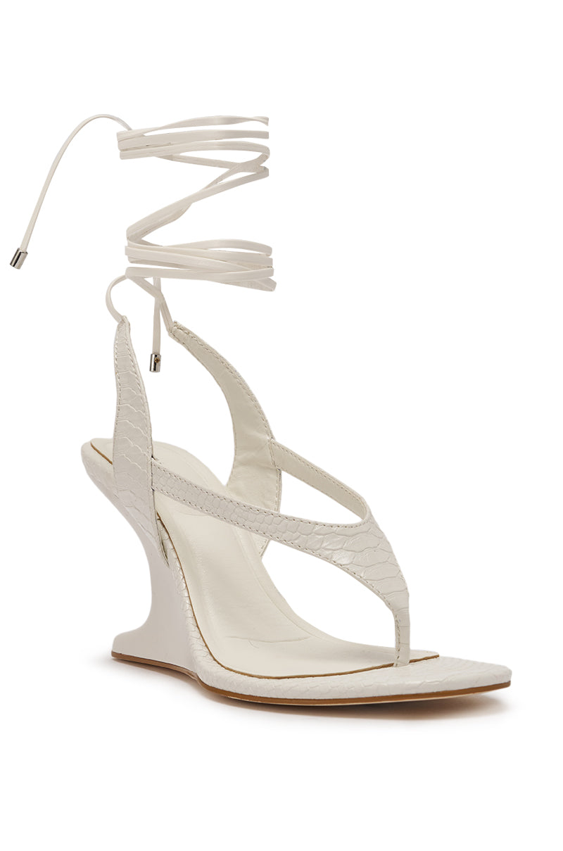 The AZALEA WANG TAMSIN White Croc Novelty Wedge Strap Sandal features faux crocodile leather, a sculpted curved heel, thong toe design, and long lace-up ankle ties with metallic tips. 5