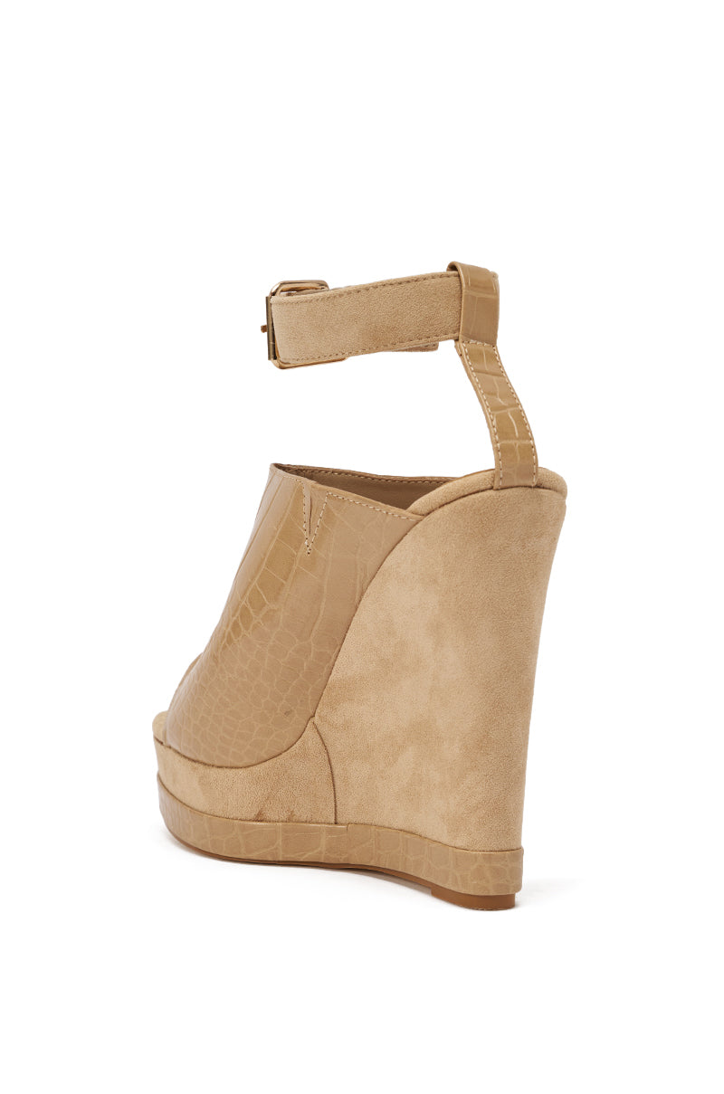 The AZALEA WANG TANA NUDE MIXED MATERIAL WEDGE features a tan crocodile-embossed faux leather upper, ankle buckle strap, comfort cushion insole, and high platform heel, shown from the back and slightly to the side. 5