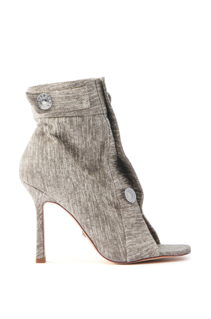 The AZALEA WANG TANDY GREY DENIM OPEN TOE BOOTIE showcases an acid-wash denim with a textured design and a fold-over, buttoned flap above the ankle. It features a slender stiletto heel, all set against a plain white backdrop.