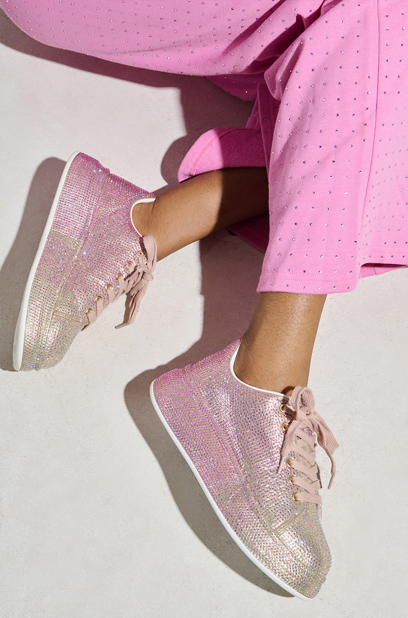 Someone in AZALEA WANG TANGY PINK OMBRE RHINESTONE SNEAKERS and pink pants with black dots is sitting on a light floor.