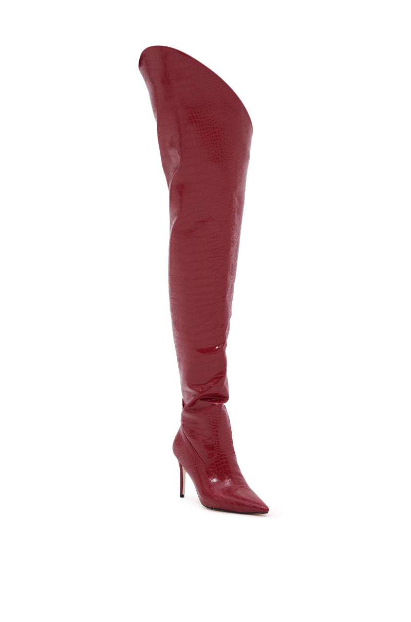 The AZALEA WANG TARRANT RED STILETTO BOOT WITH WESTERN TOPLINE features a single over-the-knee, pointy-toed silhouette in shiny crocodile-embossed red finish, with a dramatic high stiletto heel and sculptural design. 4