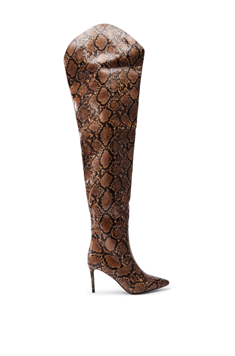 The AZALEA WANG TARRANT SNAKE WESTERN TOPLINE BOOT, a high-heeled, thigh-high boot with a striking snakeskin pattern, is displayed against a plain white background. It features a pointed toe and sleek stiletto heel, offering both style and sophistication.
