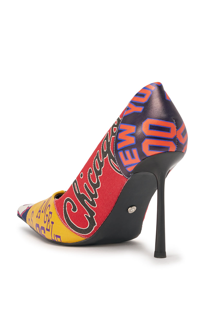 The AZALEA WANG MULTI PRINTED STILETTO POINTED TOE PUMP features a patchwork graphic with bold city names in red, yellow, and blue, a pointed toe, sleek black heel, and comfort cushion insole for all-day wear. 6