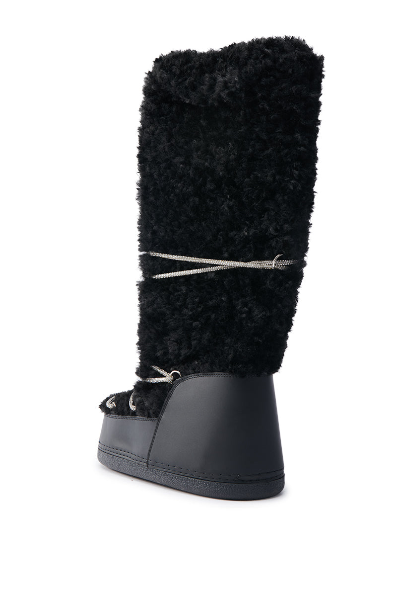 The AZALEA WANG TAYTON Black Knee High Furry Boot is shown against a white background, featuring a high, fluffy textured shaft with sleek lower parts and decorative laces that wrap around the shaft for added charm.