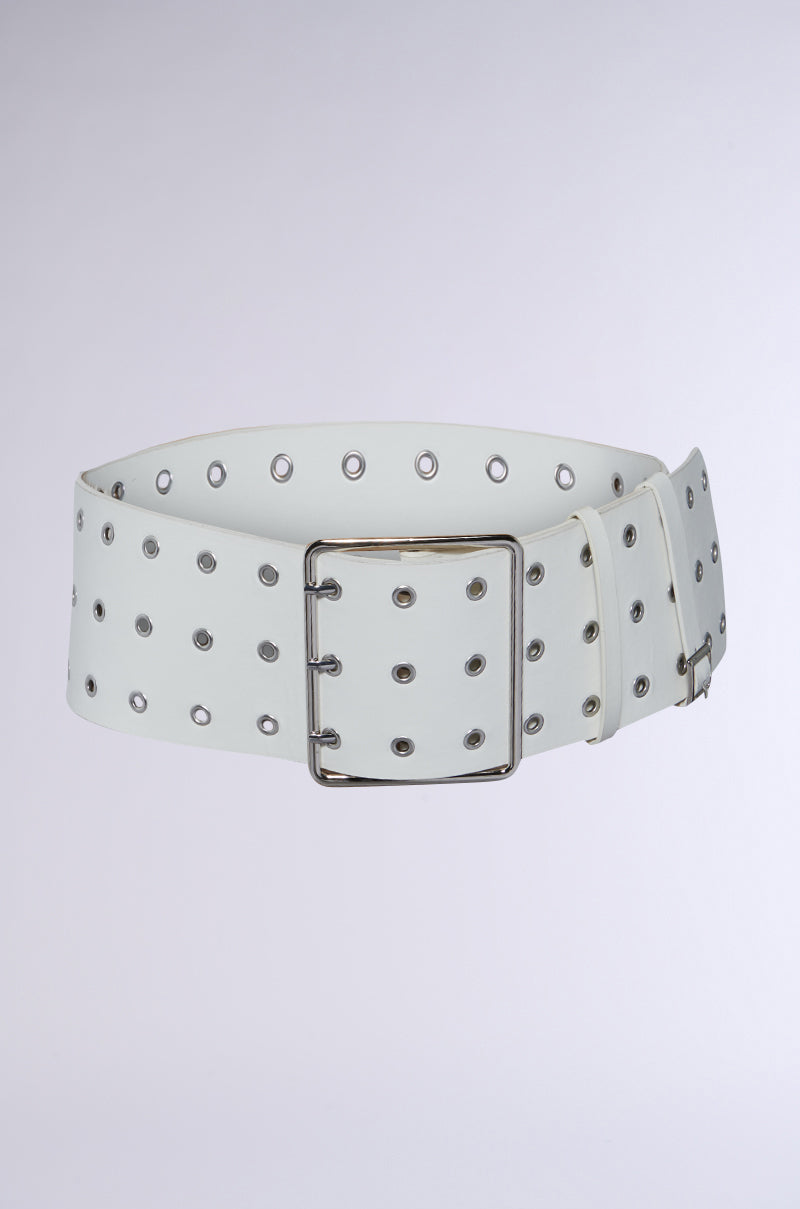 The CINCH ME IN PU BELT is a wide white faux leather belt featuring multiple rows of metal grommets and a large rectangular silver buckle, shown against a light gray background.