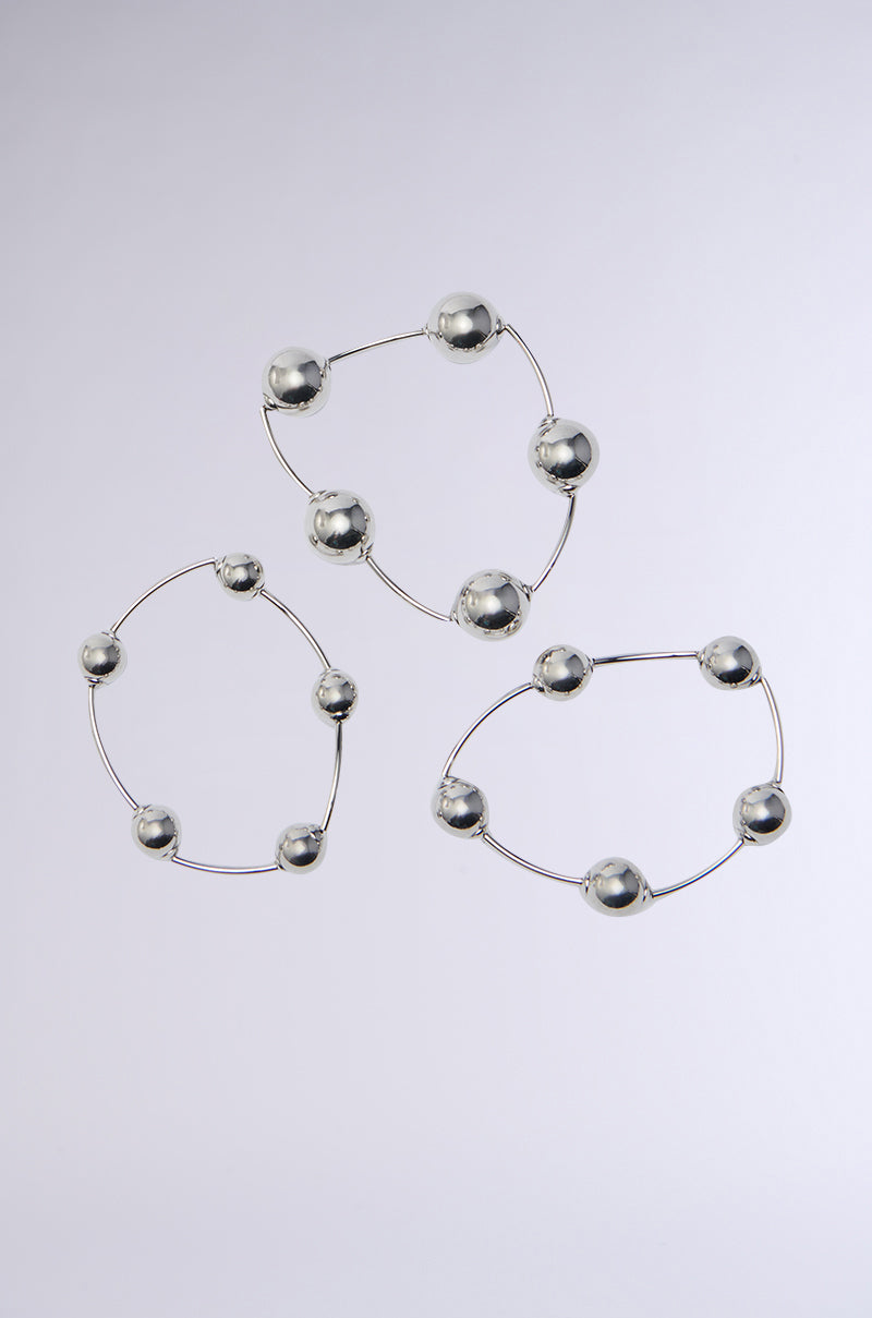 The JUST BEAD IT BRACELET SET includes three faux silver bracelets on a plain background, featuring interconnected rods and mirrored metallic beads that form a geometric pattern, emphasizing the metal's reflective shine. 2