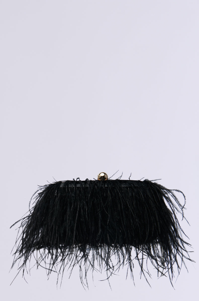 The MIDNIGHT IN PARIS FEATHER CLUTCH features an intricate feather design with a faux gold metal clasp. It includes a detachable wristlet strap for versatility, set against a plain white background.