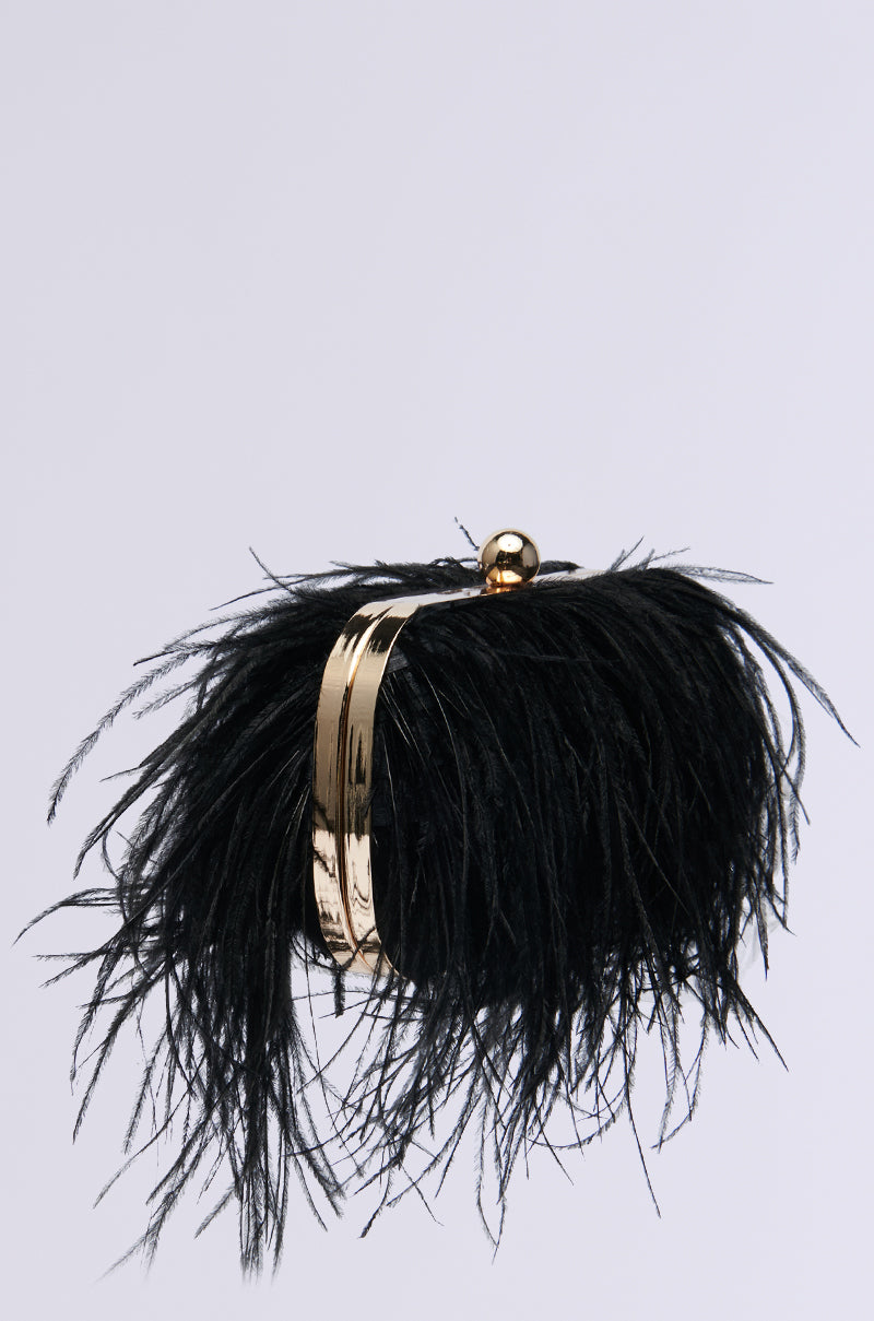 The MIDNIGHT IN PARIS FEATHER CLUTCH boasts black feathers on a light gray background, with a faux gold metal frame and clasp, plus a detachable wristlet strap.