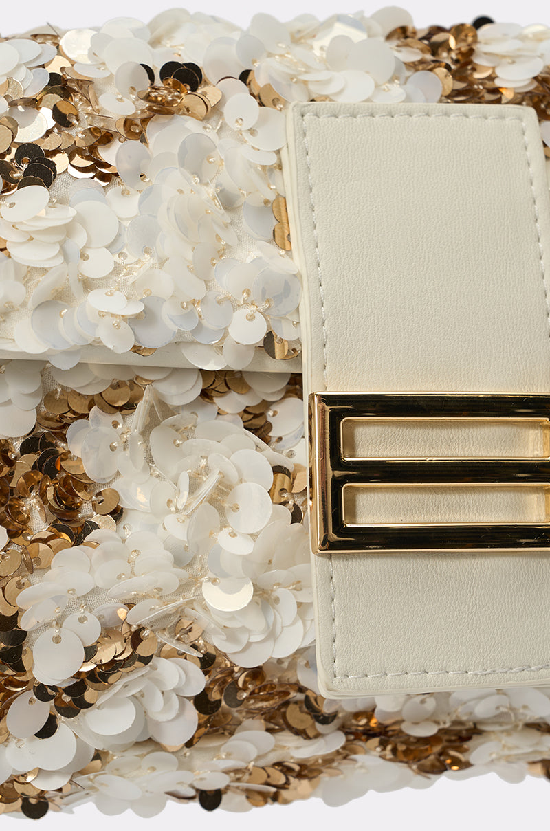 The BOUJEE BABE SEQUIN PURSE shines with gold and white sequins, a cream leather flap, and a glossy gold buckle—making it the ideal accessory for any party. 3