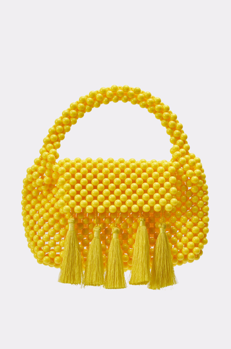 The IN THE SUN BEADED BAG is a vibrant yellow resin beaded handbag with a curved handle and four tassels, ideal as a summer purse. It’s displayed on a plain white background. 1