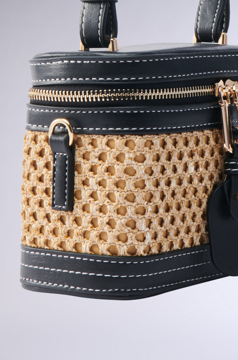 Close-up of the TAKE ME OUT WICKER PURSE, featuring an elegant and modern design with a woven tan pattern, faux leather trim, white stitching, gold hardware, zippers on top, and leather handles.