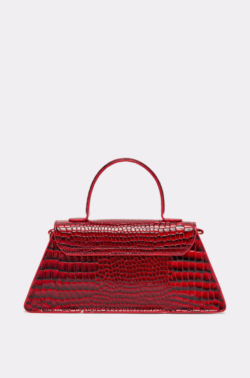 The DAY FAUX CROC PURSE is a shiny cherry red handbag in vegan crocodile leather, with a top handle, structured trapezoid shape, and detachable shoulder strap, showcased on a plain light gray background. 2