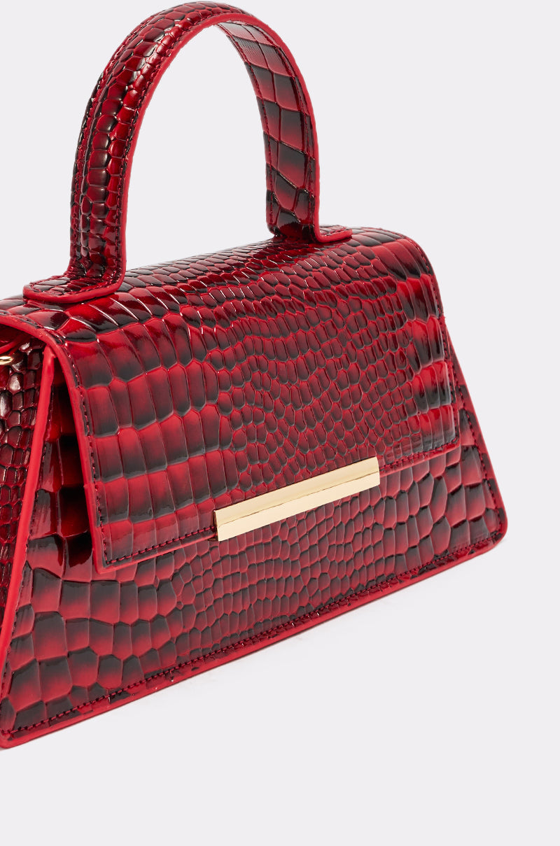 The DAY FAUX CROC PURSE in cherry red features a gold handle, adding a bold and stylish touch to any outfit.