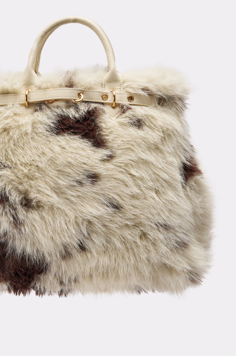 The MOO FAUX FUR MINI TOTE is a small handbag covered in soft white and brown cow print faux fur, featuring cream handles and gold hardware. 4