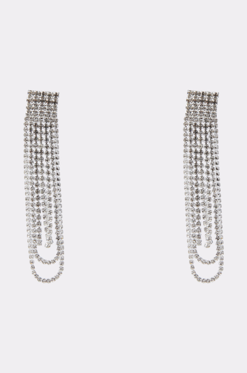 The EXTRA LUXE DANGLE EARRING IN SILVER features a silver metallic base and cascading rows of sparkling rhinestone chain links in a layered, draped design, shown against a plain white background.