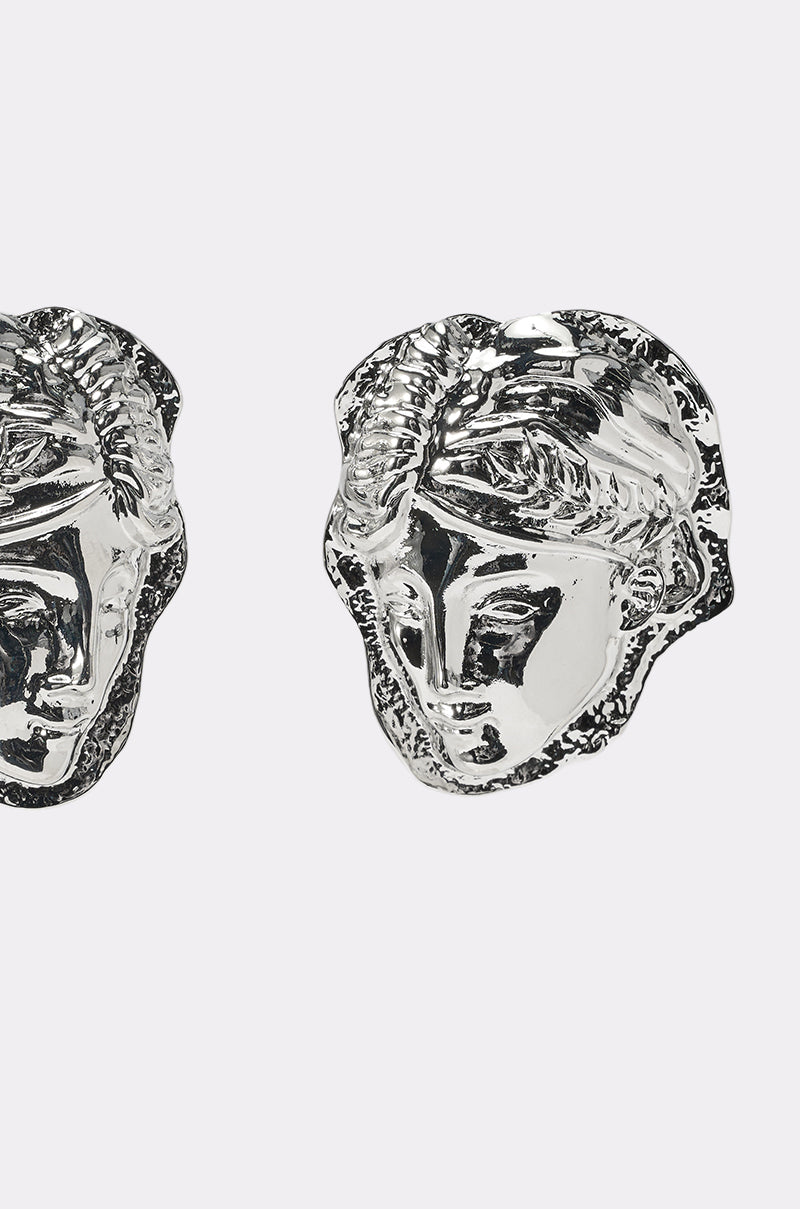 Close-up of the IM IN ITALY EARRING—silver, metallic, abstract classical head-shaped earrings. Partial faces are visible, emphasizing the artistic vintage allure of these statement pieces against a white background. 3