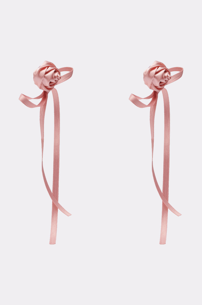 Two pink satin ribbon roses, inspired by the COQUETTE LOVE EARRING, display long trailing ribbons and are arranged side by side on a plain light background. 3