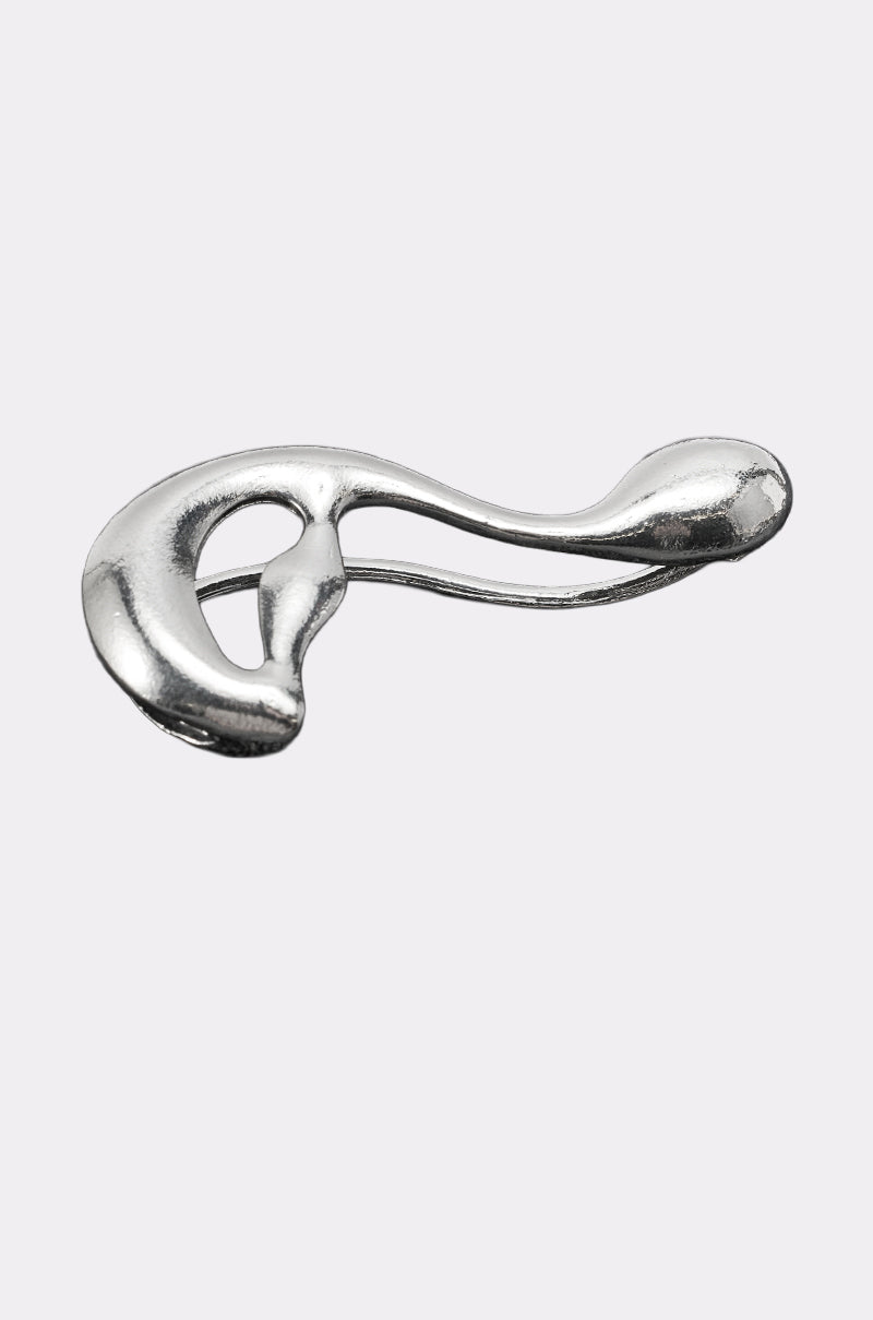 The STEF EAR CUFF is a shiny, abstract silver ear cuff featuring smooth, flowing curves and an open, organic shape, displayed on a plain light gray background. 2