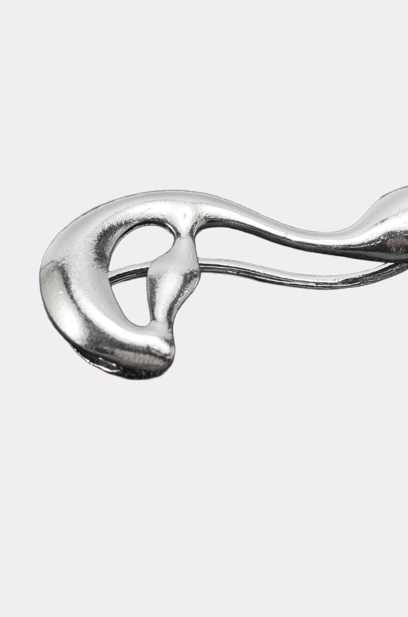 A close-up of the STEF EAR CUFF, a shiny abstract silver accessory with smooth, flowing curves, showcased against a plain light gray background. 5