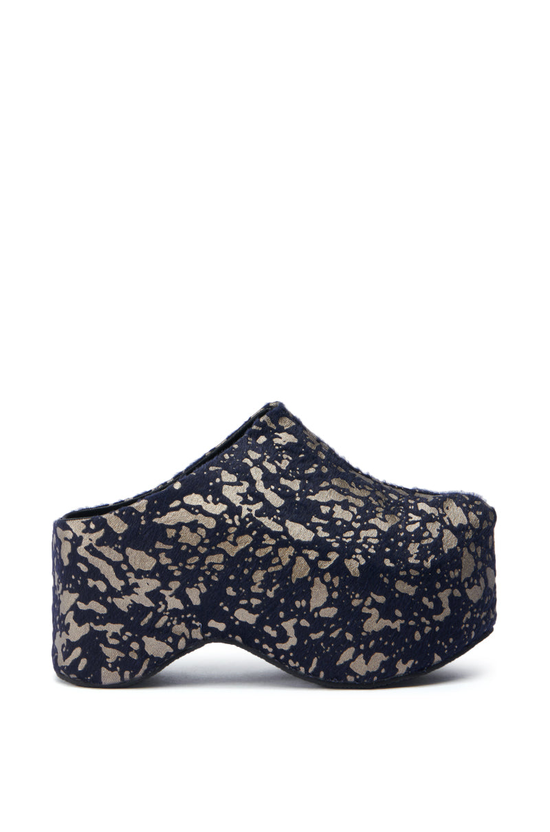 Behold the AZALEA WANG TEATREE BLACK CLOG: a side-profile image reveals its elegant platform mule silhouette with a dark blue base adorned in a metallic silver speckled pattern. The design incorporates a chunky heel, thick sole, and convenient slip-on style, seamlessly merging fashion and comfort.