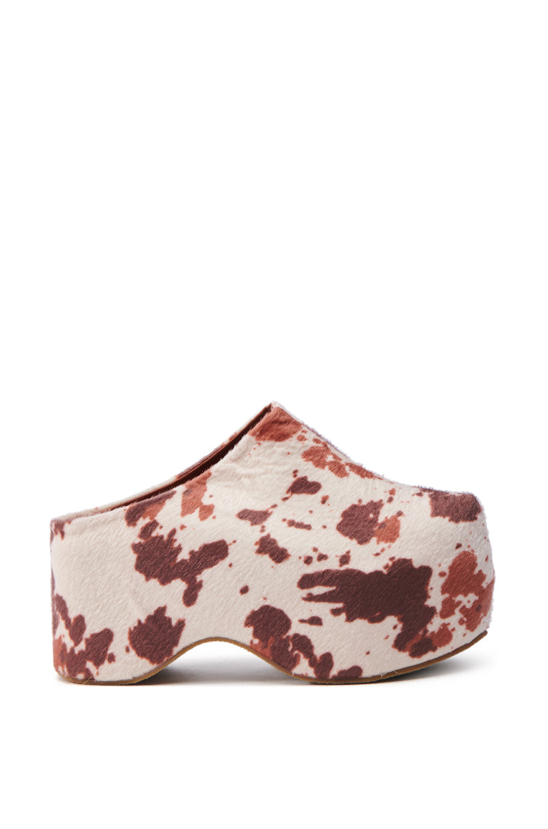 The AZALEA WANG TEATREE COW CLOG features a brown and white cow print with a thick platform sole and closed toe, crafted from faux pony hair for an artistic flair, complete with a comfort cushion insole for all-day coziness.