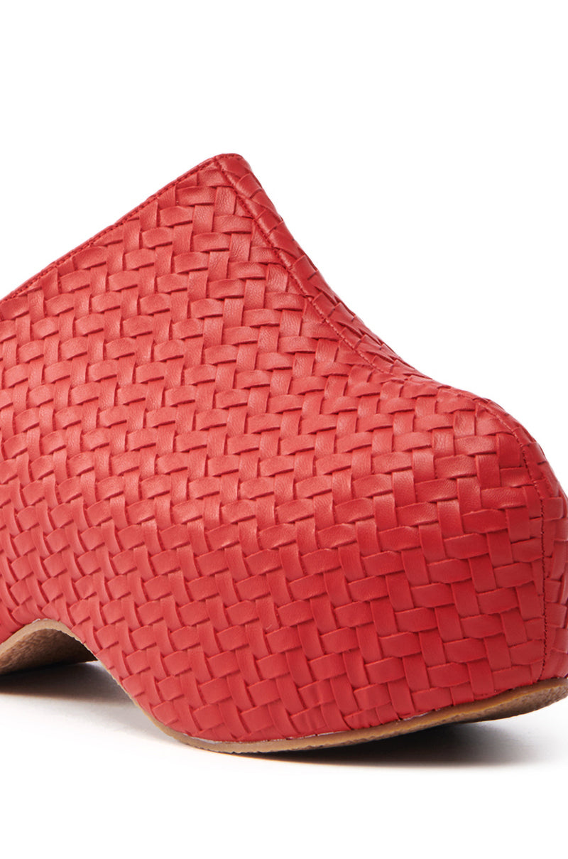 The AZALEA WANG TEATREE RED CLOG is showcased in a close-up image, highlighting its red vegan leather construction with a basket-weave texture, chunky heel, and rounded toe against a white background.