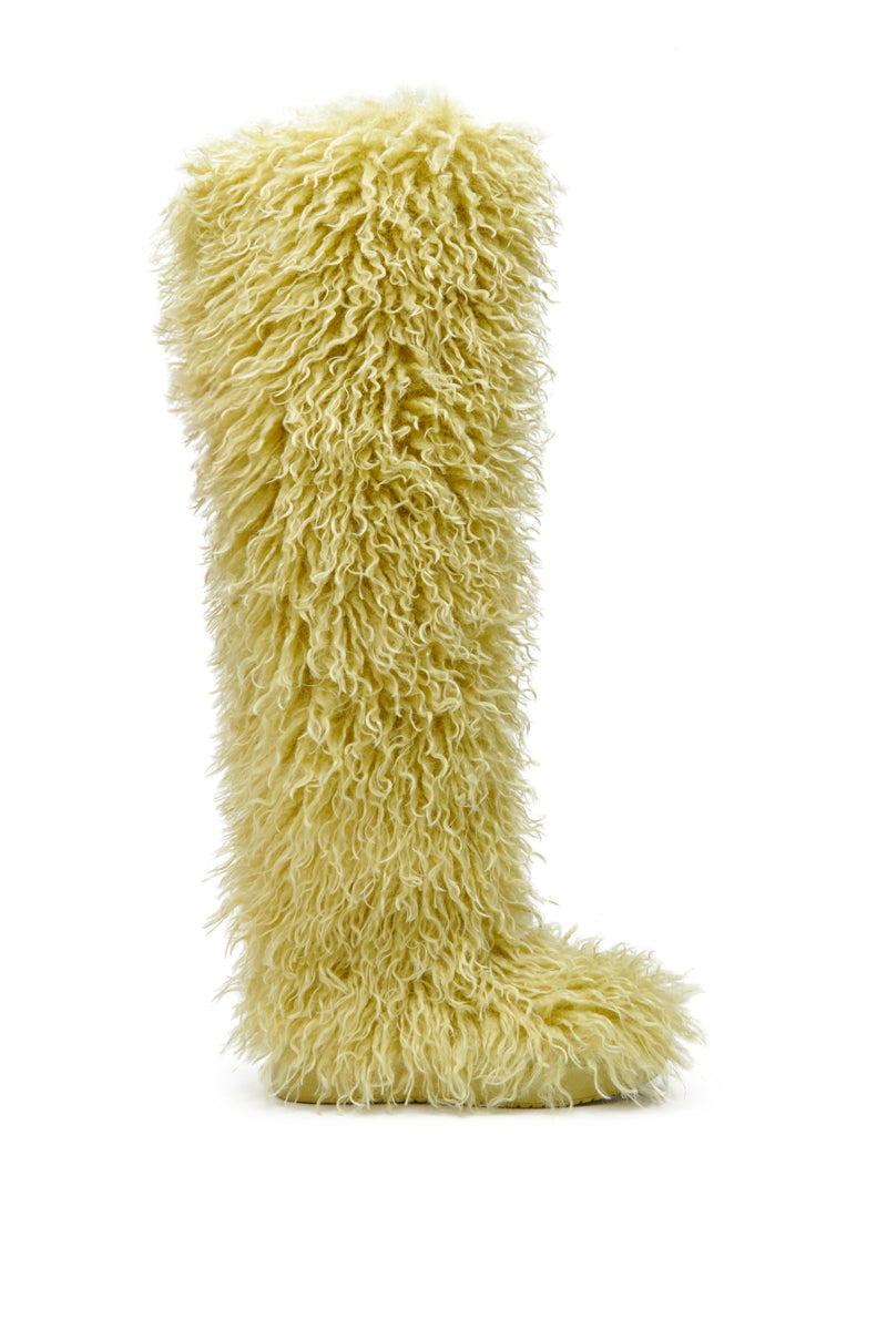 A single AZALEA WANG TEMPLETON LIME POODLE FUR OVER THE KNEE BOOT, covered in shaggy pale yellow faux fur, stands upright against a white background—perfect for making a statement with these bold faux fur boots.