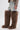 A person wears knee-length distressed denim shorts, a snakeskin-print jacket, and AZALEA WANG TEMPLETON TAUPE POODLE FUR OVER THE KNEE BOOT—oversized brown faux fur boots extending above the knees against a plain white background.