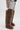 A person in ripped denim shorts, a snakeskin jacket sleeve, and knee-length AZALEA WANG TEMPLETON TAUPE POODLE FUR OVER THE KNEE BOOTS stands against a plain white background.