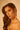 Under warm, golden lighting, a woman with long, wavy brown hair and a serious expression showcases the bold DONATELLA EARRING as she looks into the camera.