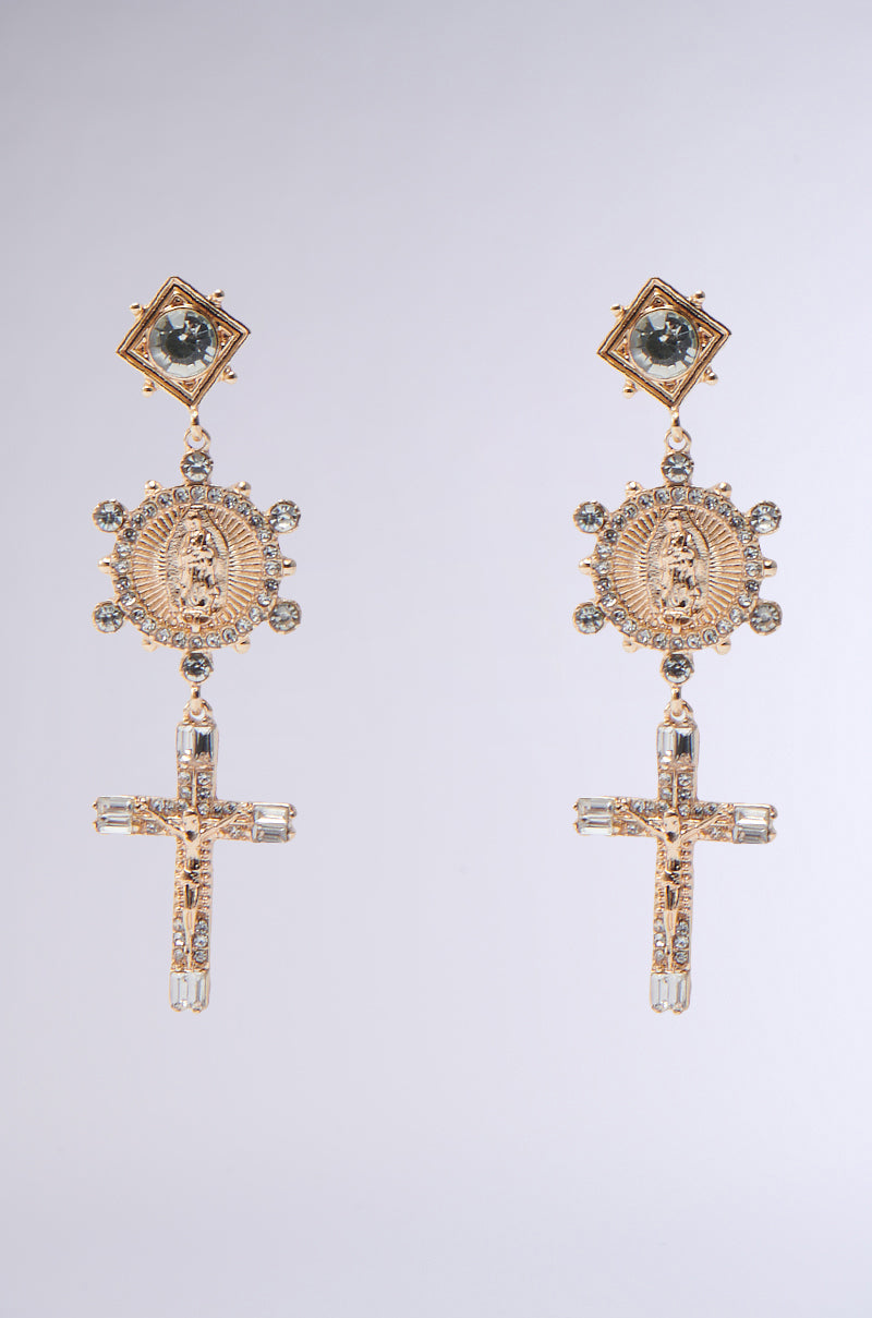 Introducing the CROSS MY HEART EARRING: gold beauties with a square gem, intricate medallion, and jeweled cross pendant on a plain gray backdrop. They captivate with their rhinestone center allure.
