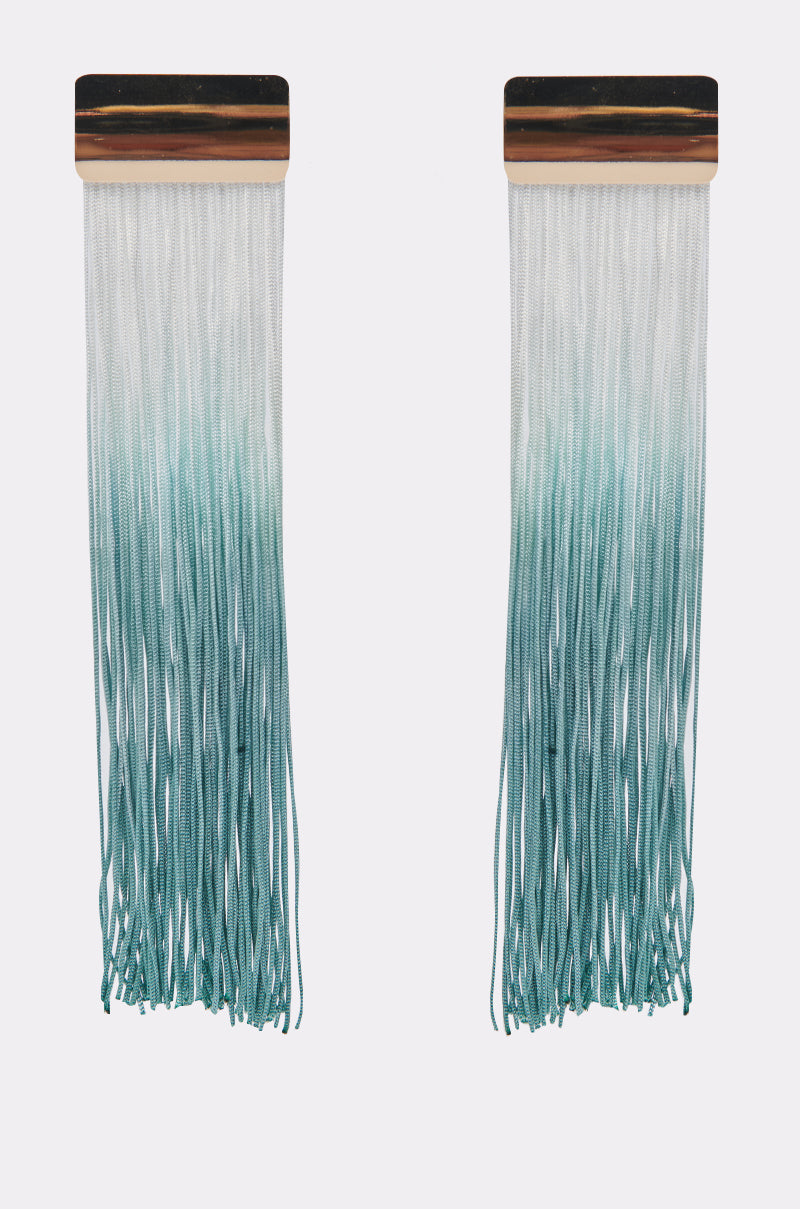 The REBRAND EARRING features long tassel fringe with rectangular tops and strands that fade from white to teal in a bold blue ombre gradient, making a striking statement. 1