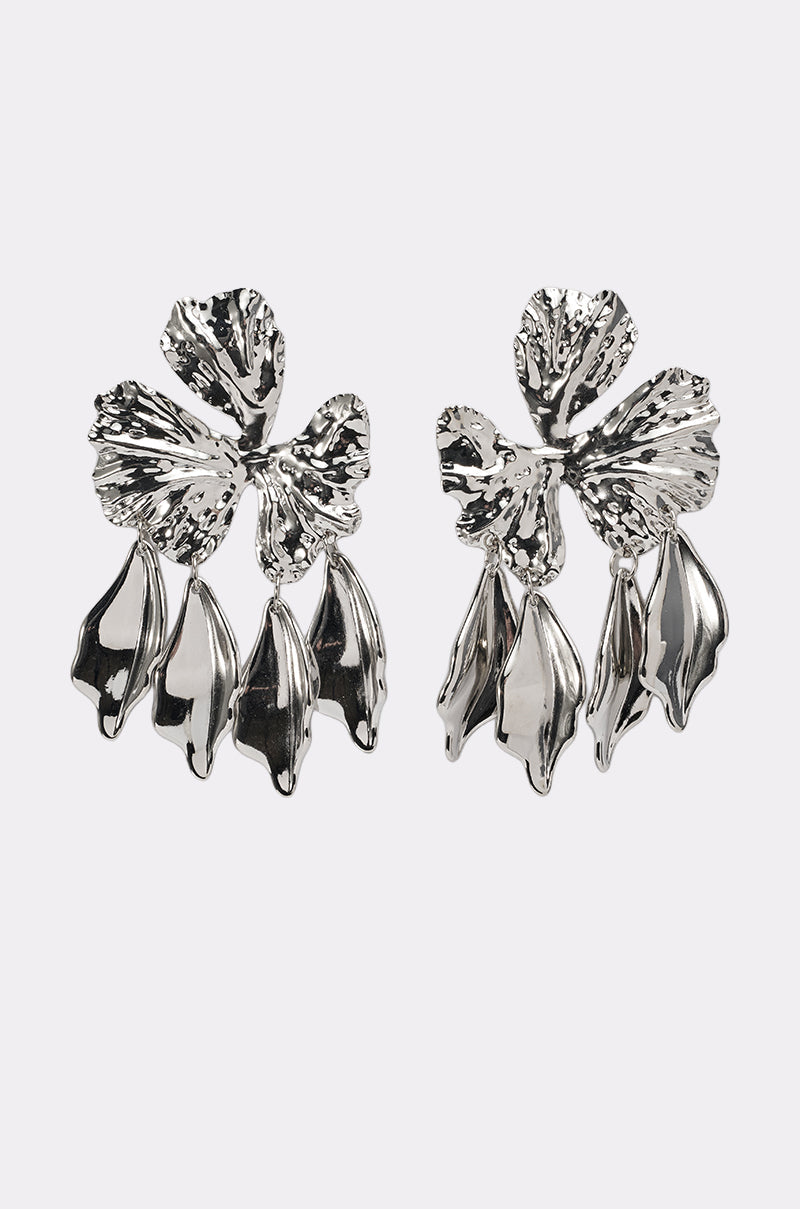 The IN BLOOM EARRING features shiny, silver-tone statement earrings shaped like abstract flowers with textured petals and three dangling leaf-like elements on each. 4