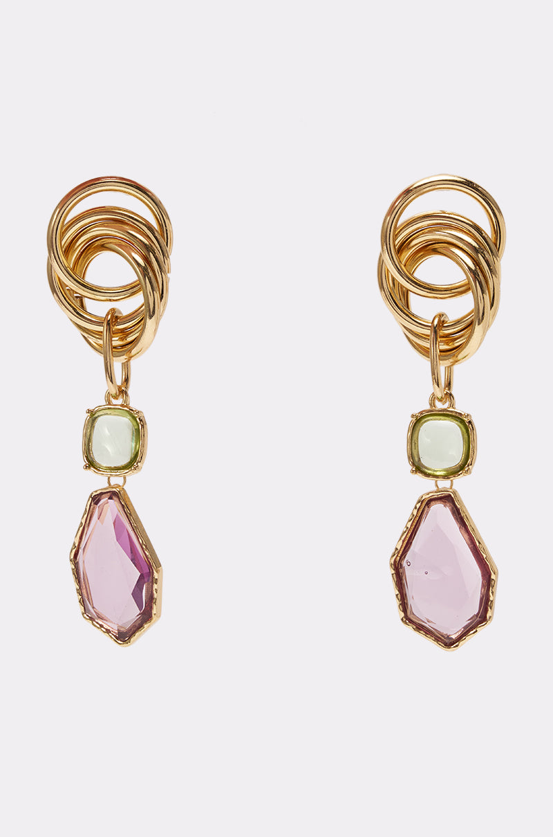 MODERN MUSE STATEMENT EARRINGS feature interlocking gold loops, a small square green stone, and a striking large irregular pink gemstone drop, creating bold pink and green earrings perfect for wedding accessories. Shown against a white background.