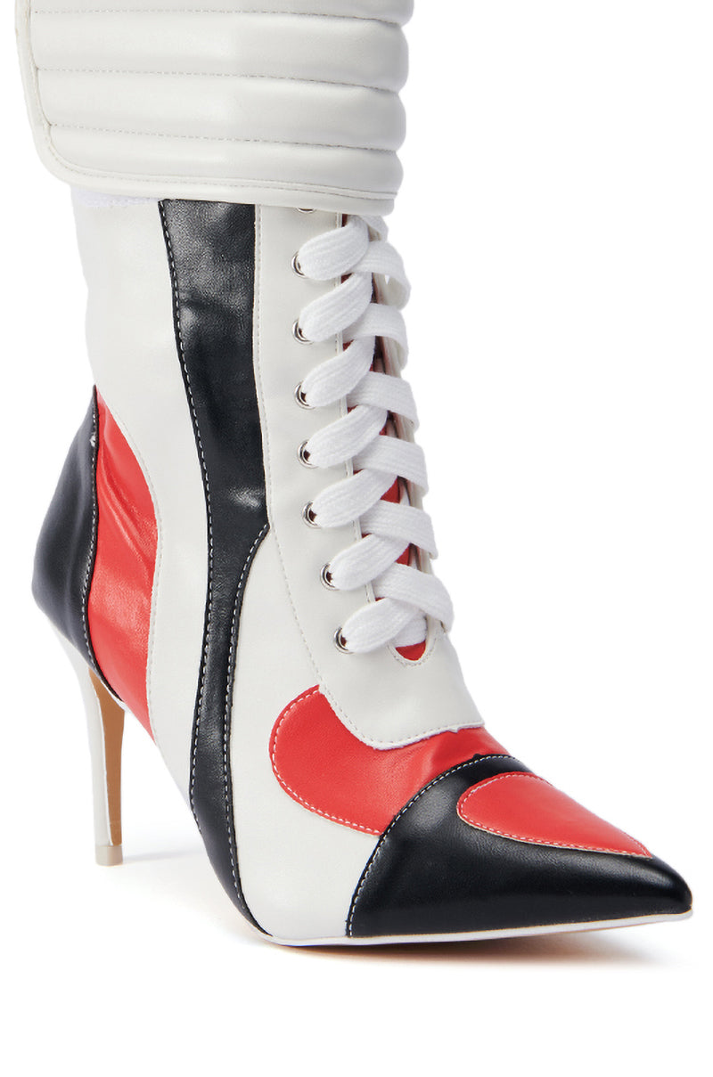 Introducing the TESS MULTI RACER BOOTIE: a fashionable women's high-heeled ankle boot with a pointed toe, showcasing a chic color block design in white, red, and black. This faux leather bootie features elegant white laces, a sleek stiletto heel, and quilted white padding around the ankle for added style and comfort.