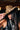 A woman with long dark hair in a black sleeveless top partially covers her face with the CHECK ME OUT FAUX FUR COWBOY HAT, a bold leopard print western accessory, styled with layered silver cross necklaces for added edge.