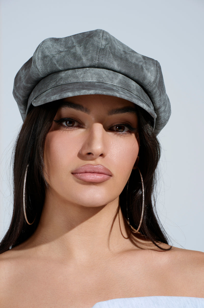A woman with long dark hair wears the gray IT GURL PU BRIM HAT, large hoop earrings, and natural makeup. She looks directly at the camera against a light background.