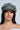 A woman with long dark hair wears the gray IT GURL PU BRIM HAT, large hoop earrings, and natural makeup. She looks directly at the camera against a light background.