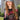 A young woman with long, wavy hair wears the IT GURL PU BRIM HAT in gray and a black mesh top with red sequined "AUTHENTIC 25" text, outdoors in a city park with skyscrapers behind her.