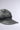 A close-up of the IT GURL PU BRIM HAT shows its gray denim fabric and faux leather brim, with detailed stitching and subtle AKIRA Label flair, set against a light gray background and angled to highlight its textured look.