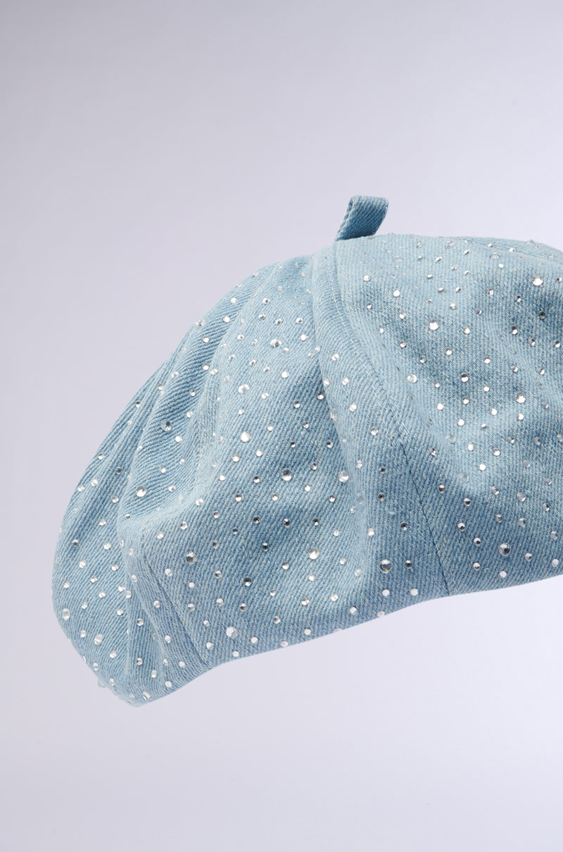 The SEE ME COMING BLING BERET is a blue accessory with small white polka dots on a light gray background. It has a classic shape with subtle rhinestones and is topped with a small fabric loop.