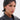 Wearing the ELI BLING HAIR TUBAN, a person with short dark hair, facial piercings, and a black leather jacket looks confidently at the camera against a plain background.