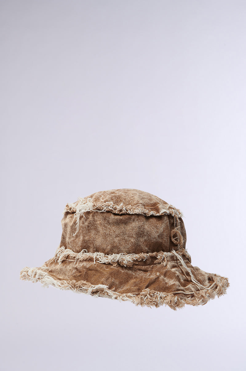 The WITH IT DISTRESSED BUCKET HAT features a wide brim, frayed edges, and a worn brown finish in vintage-washed fabric, displayed on a plain light gray background.
