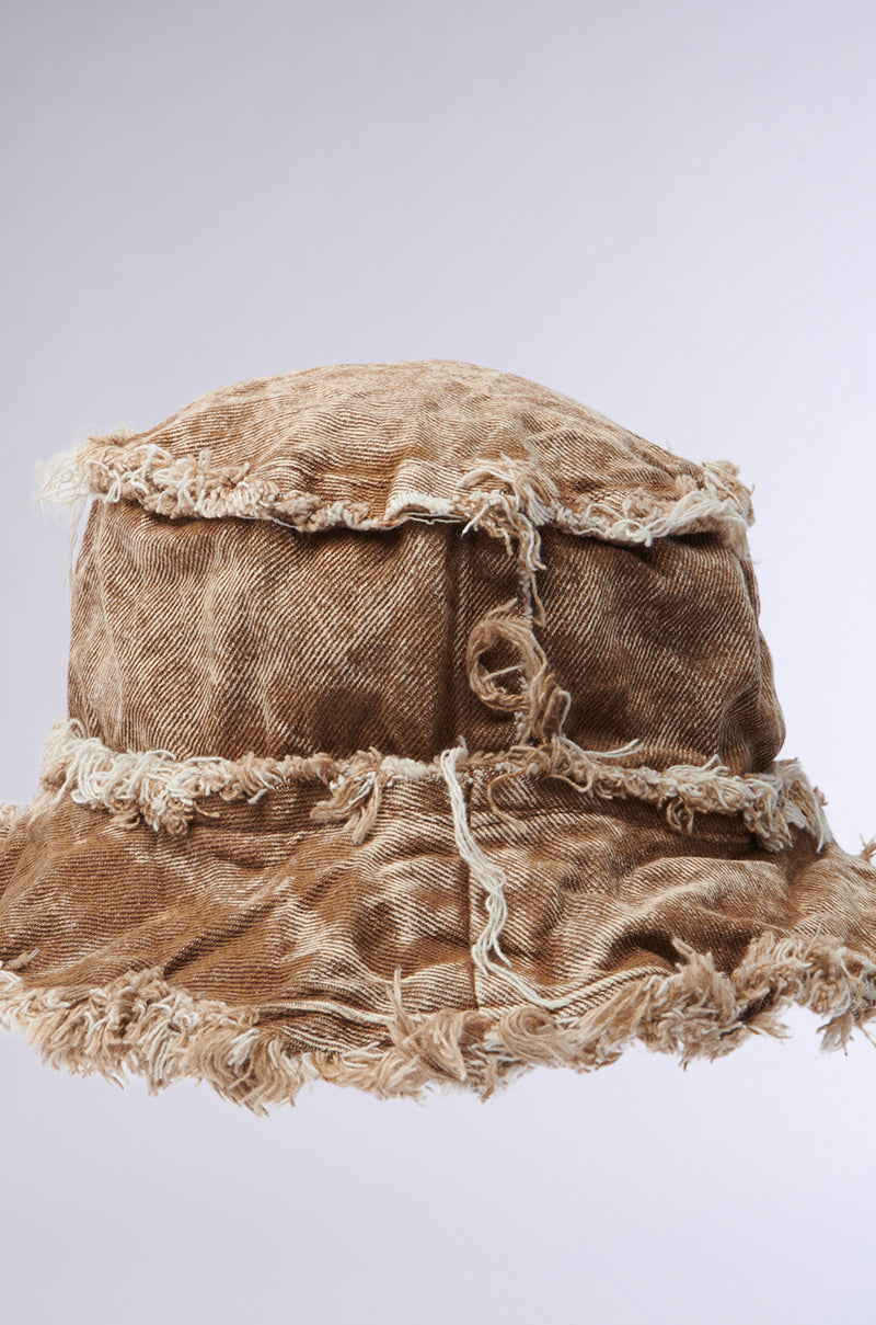 The WITH IT DISTRESSED BUCKET HAT, featuring brown vintage-washed fabric, frayed edges, and visible seams, is shown against a plain light gray background.
