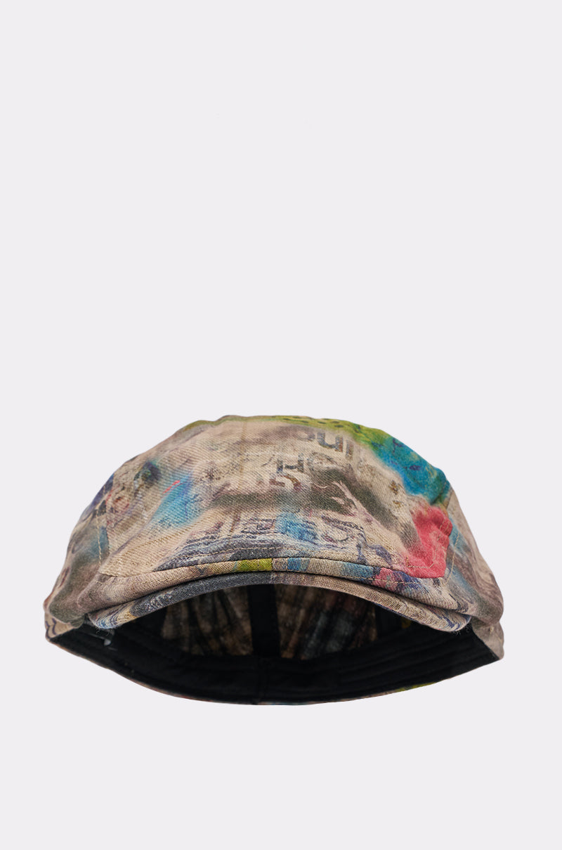 The IM OUTSIDE GRAFFITI HAT is shown on a plain light gray background, featuring a curved brim, multicolored abstract patterns and text in blue, green, and beige, plus an adjustable headband for comfort. 2
