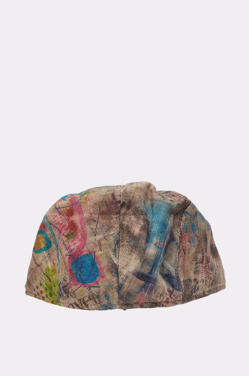 The IM OUTSIDE GRAFFITI HAT is a round newsboy-style cap with an abstract multicolored pattern—blue, pink, yellow, and green on beige—plus an adjustable headband. Shown against a white background. 4