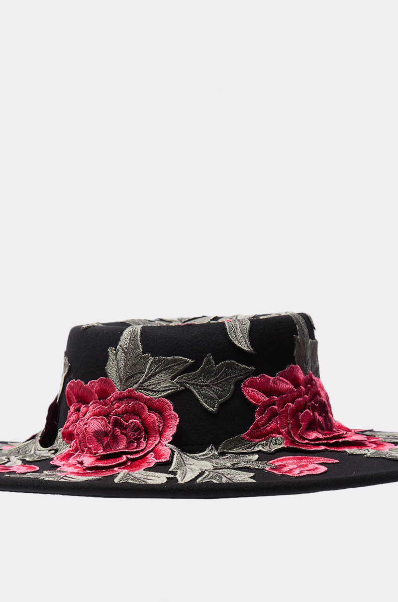 The ALIYA FLORAL BRIM HAT is a black, wide-brim hat with detailed red flower and green leaf embroidery set on a simple light background. 3