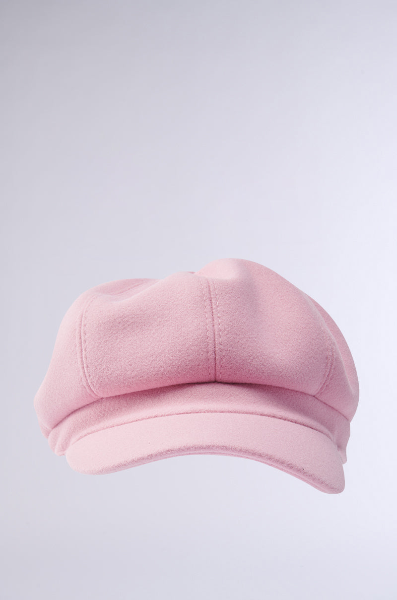 A PRETTY IN PINK BRIM HAT is displayed on a gray backdrop, highlighting its soft, rounded crown and flexible base. It features a flat visor, blending style with casual elegance.